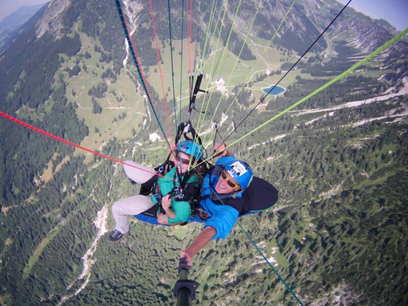 Begeisterte Gleitschirmflieger beim Tandemflug über den Bergen